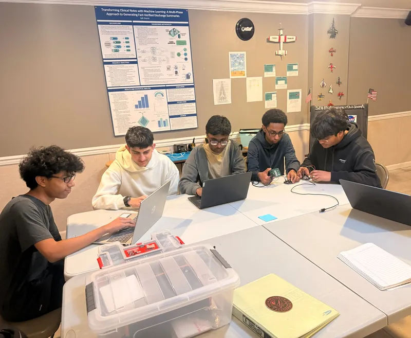 Five team members working at a long table during a payload build session