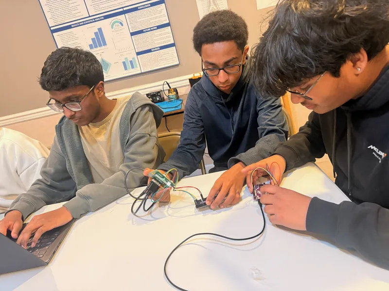 Three team members connecting payload electronics at a table