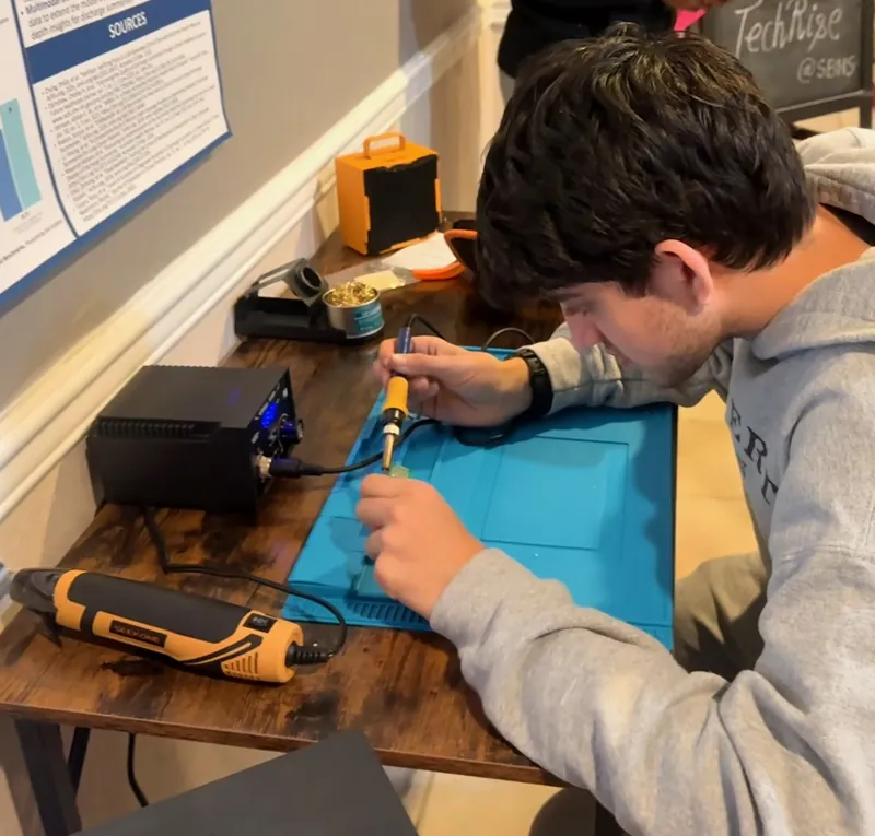 A team member soldering at a workbench with a blue silicone mat