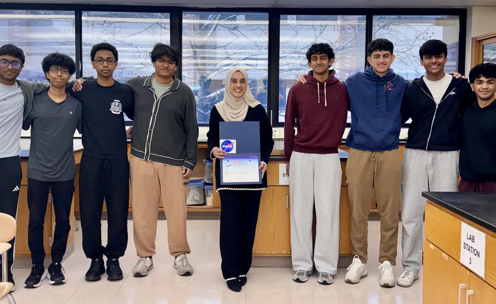 SBHS Aerospace Club TechRise team members and advisor Ms. Chishti holding the NASA TechRise Student Challenge certificate in a school lab